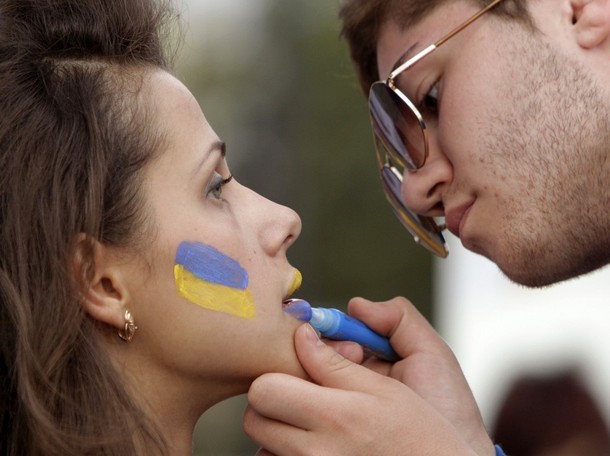 Một người đàn ông vẽ lá cờ Ukraina lên khuôn mặt xinh đẹp của một cô gái trẻ. Hình ảnh được chụp tại một fan zone của UEFA ở Kharkiv, Ukraina.